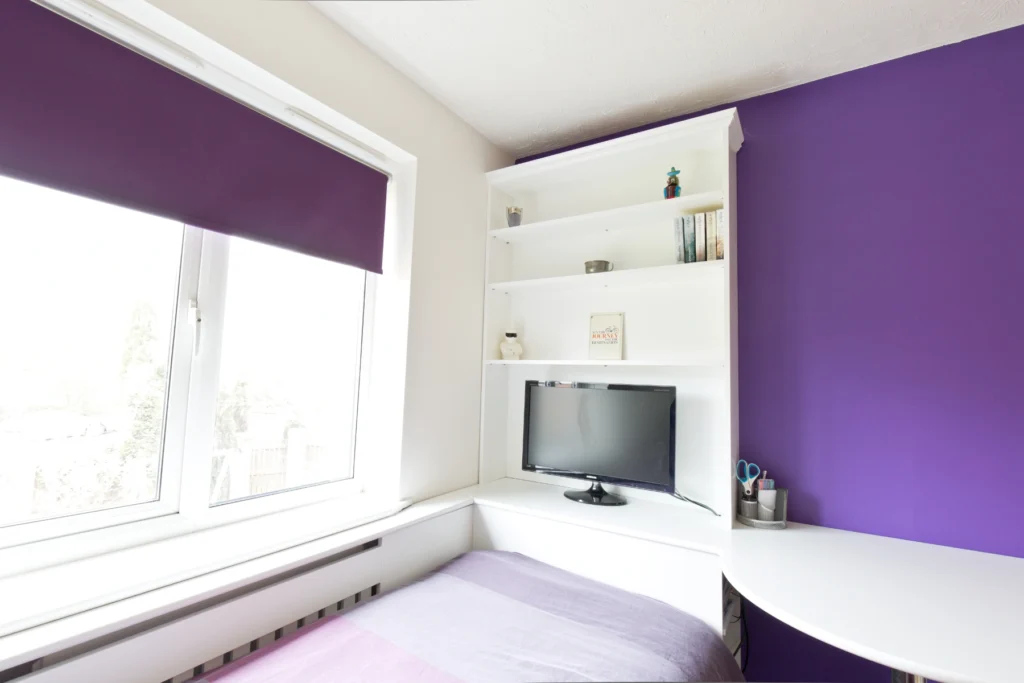Teen boys room with tv area at teh base of bed and draswers below bed